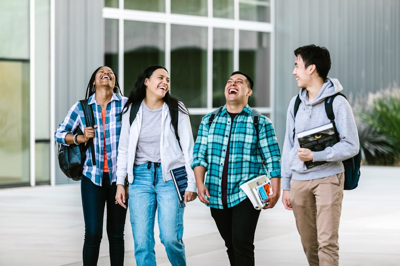Group of diverse college students laughing and walking on campus.